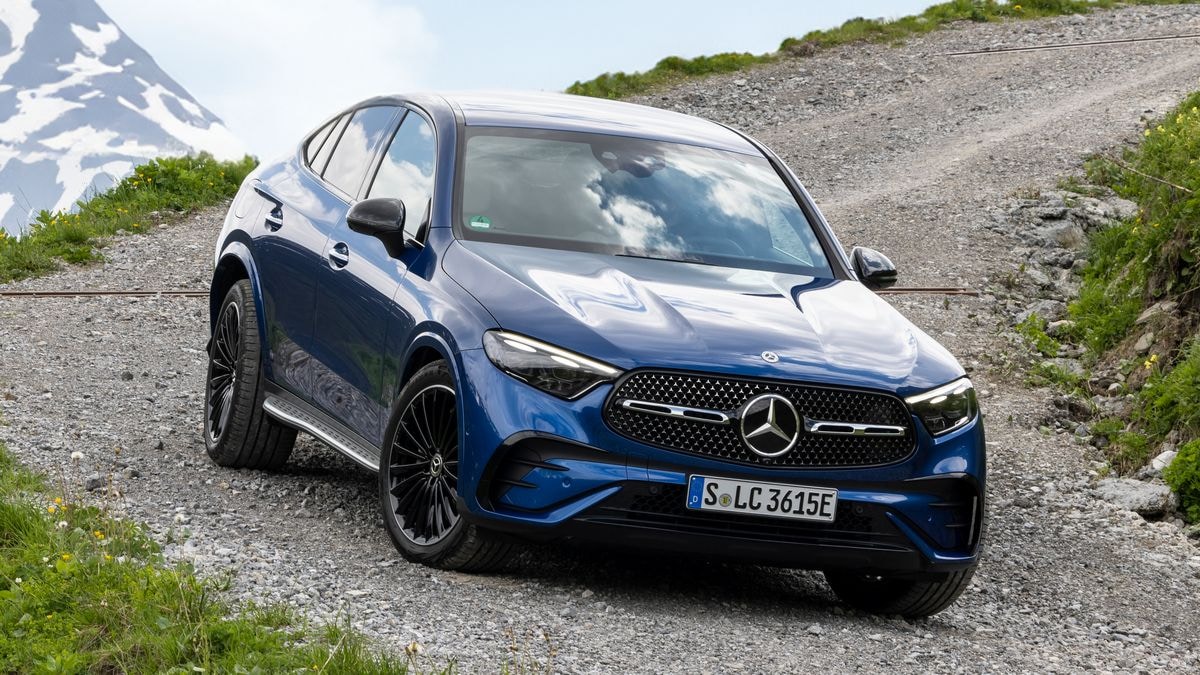2024 Mercedes-Benz GLC 300 4MATIC Coupe in blue on a gravel road with a snowy mountain in the background.