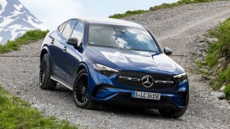 2024 Mercedes-Benz GLC 300 4MATIC Coupe in blue on a gravel road with a snowy mountain in the background.