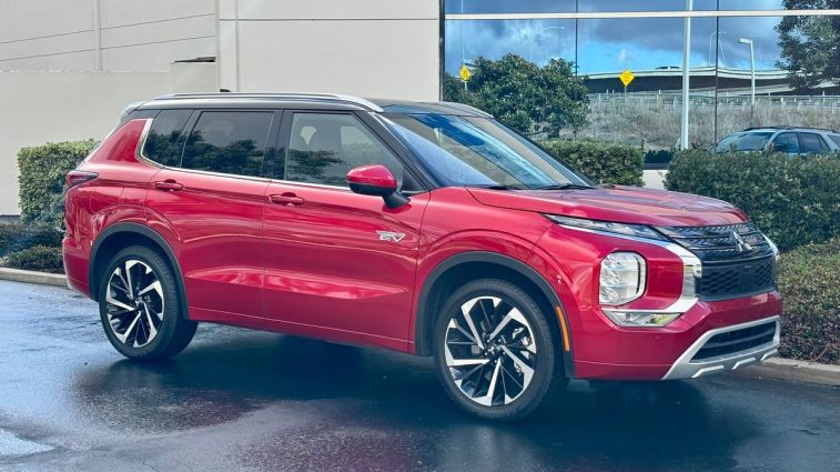 2024 Mitsubishi Outlander PHEV in red parked next to a building.