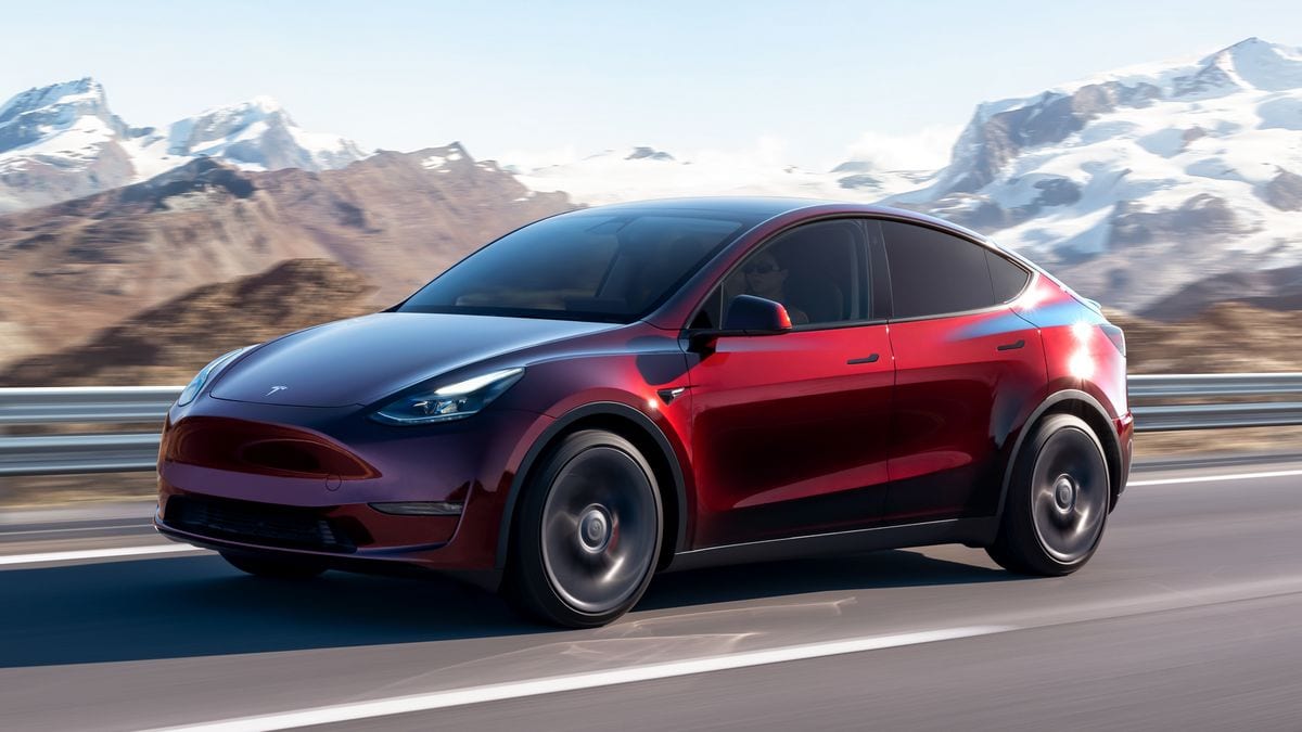 2024 Tesla Model Y in red with a snow covered mountain range in the background.