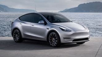 2024 Tesla Model Y in silver with the ocean in the background.