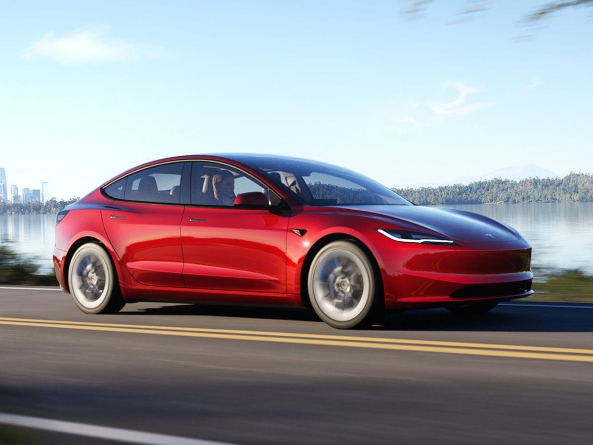 2024 Tesla Model 3 driving down a road.