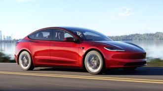 2024 Tesla Model 3 driving down a road.