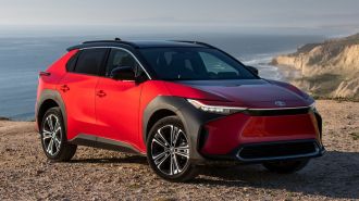 2024 Toyota bZ4X Limited in Super Sonic Red with the ocean in the background.