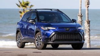 2024 Toyota Corolla Cross Hybrid SE in Blue Crush Metallic with the ocean in the background.