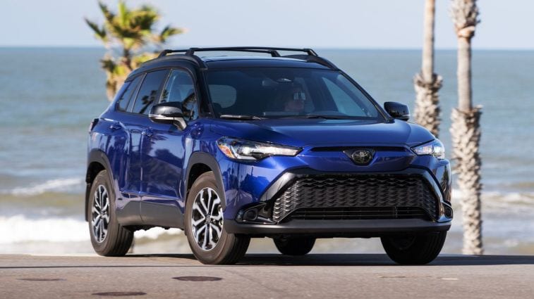 2024 Toyota Corolla Cross Hybrid SE in Blue Crush Metallic with the ocean behind.