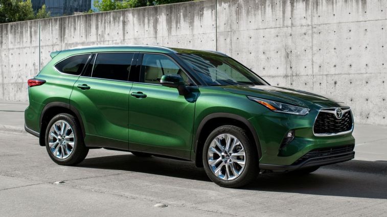 2024 Toyota Highlander Limited in Cypress Green parked next to a concrete wall.