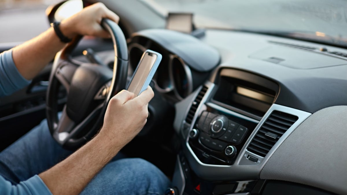 a driver looks at their cell phone behind the wheel