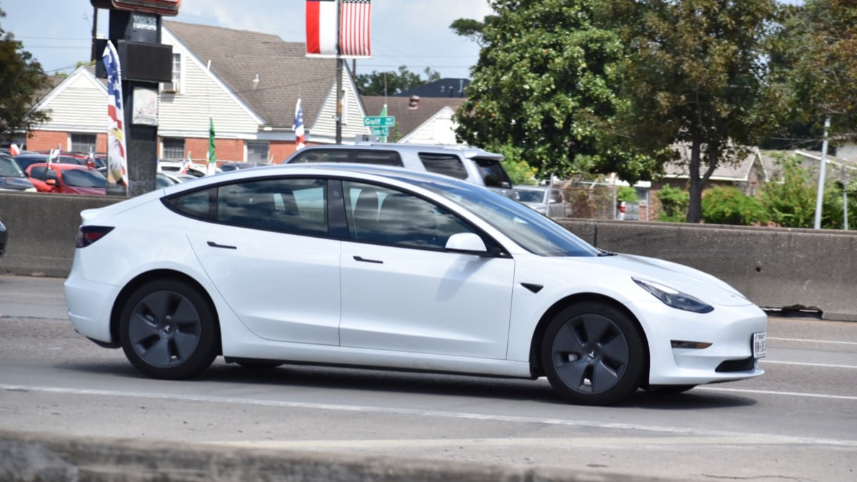 A Tesla Model 3 underneath the flags of Texas and the United States