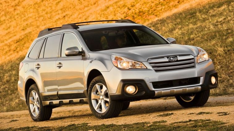2013 Subaru Outback on a dirt road at sunset.