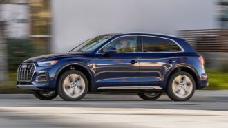2024 Audi Q5 Prestige in Navarra Blue driving down a street.