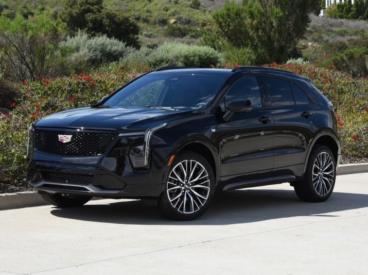 كاديلاك XT4 2024 باللون الأسود مع شجيرات في الخلفية.