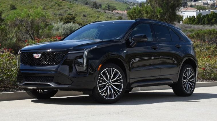 2024 Cadillac XT4 in black with shrubs in the background.