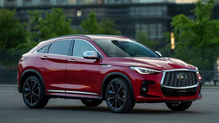 إنفينيتي QX55 2024 باللون الأحمر مع مبنى سكني في الخلفية.