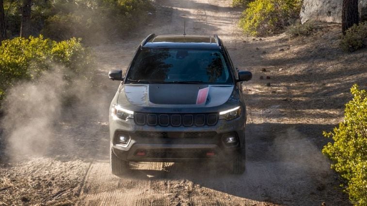 2024 Jeep Compass Trailhawk driving down a dirt road.