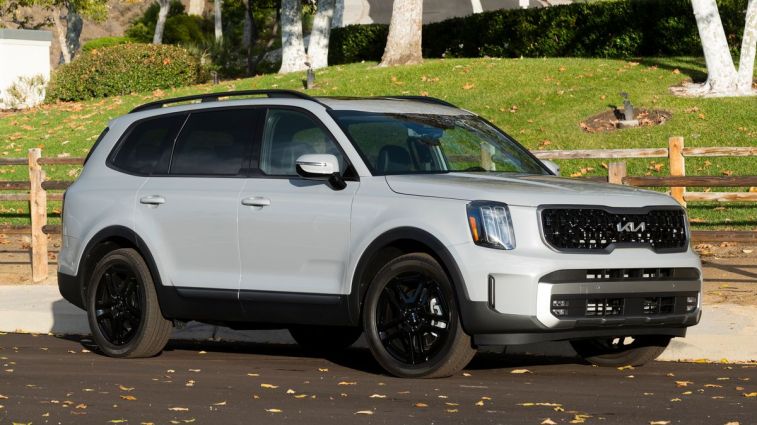 2024 Kia Telluride X-Line in grey with a wooden fence in the background.