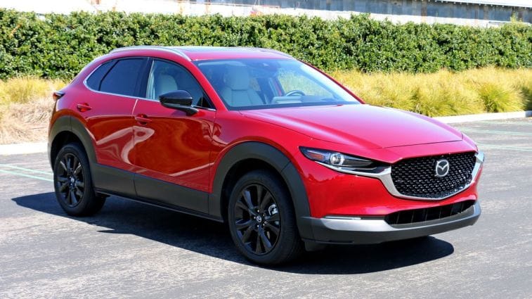 2024 Mazda CX-30 in red with bushes and a barn in the background.