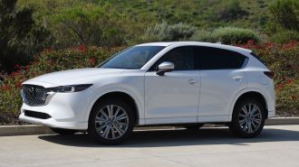 2024 Mazda CX-5 Signature in white with shrubs in the background.