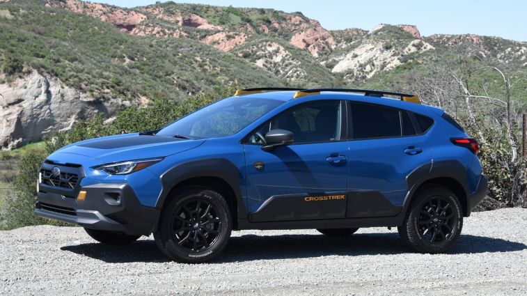 2024 Subaru Crosstrek Wilderness in blue with hills in the background.