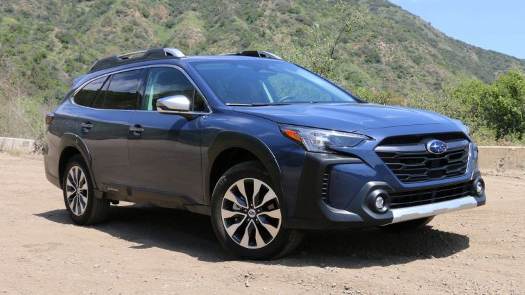 2024 Subaru Outback Touring parked on a dirt road with hills in the background.