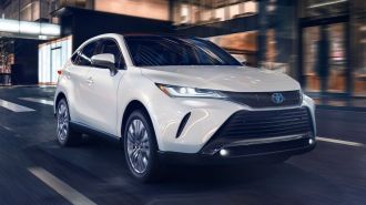2024 Toyota Venza Limited in white driving down a street at night.