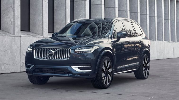 2024 فولفو XC90 Recharge T8 AWD باللون الأزرق الدنيم متوقفة بالقرب من أحد المباني.