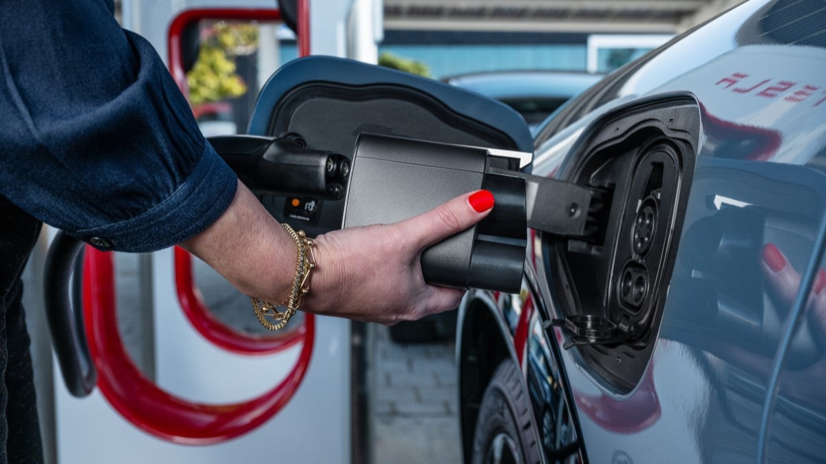 A Ford EV owner plugs into a Tesla Supercharger using an adapter