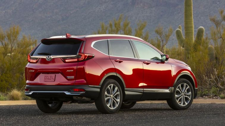 2021 Honda CR-V Hybrid in red with bushes and cacti in the background.