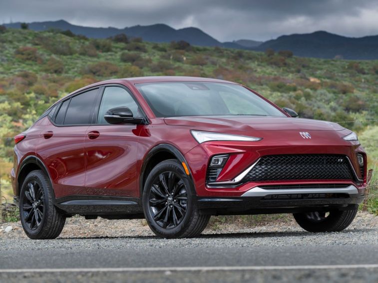 2024 Buick Envista Sport Touring in Cinnabar Metallic with green hills in the background.