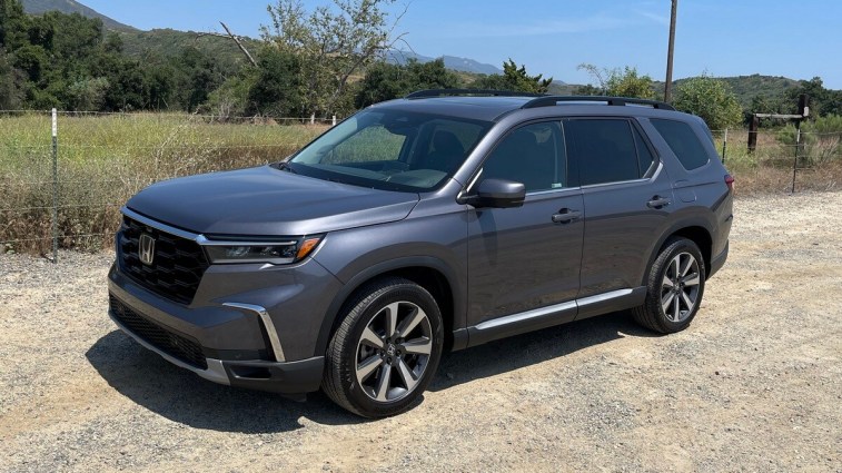 2024 Honda Pilot Elite in grey with grass and trees in the background.