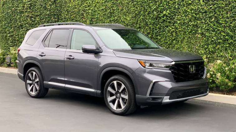 2024 Honda Pilot Elite in grey with green ivy in the background.