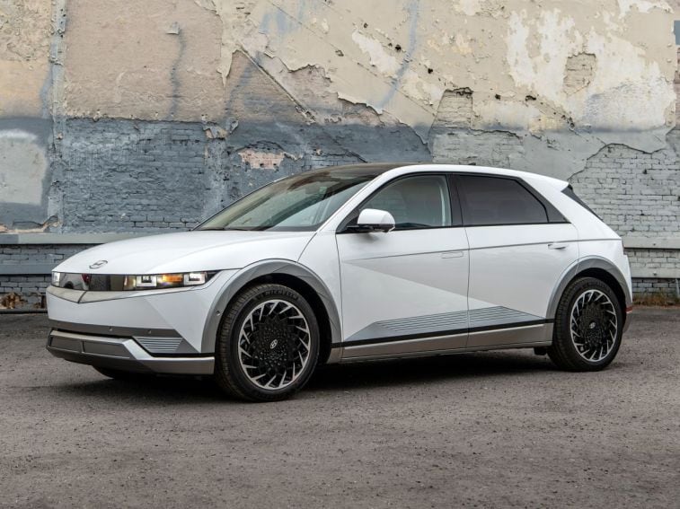 2024 Hyundai Ioniq 5 in white with a peeling brick wall in the background.