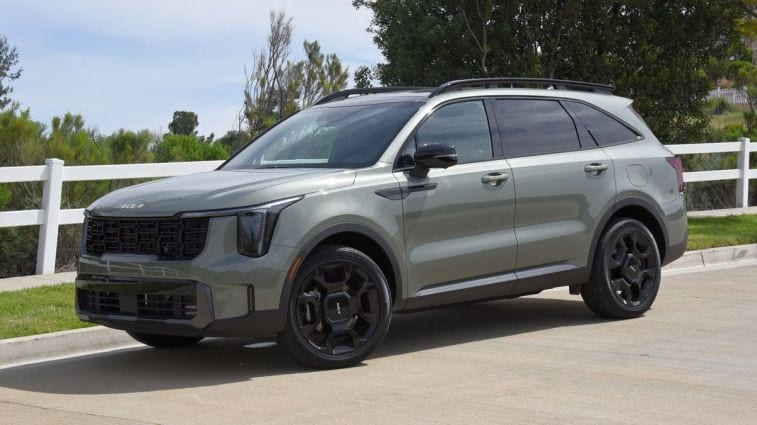 2024 Kia Sorento X-Line in Jungle Green with a white fence in the background.