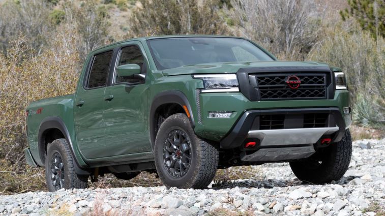 2024 Nissan Frontier PRO-4X parked on gravel with trees in the background.