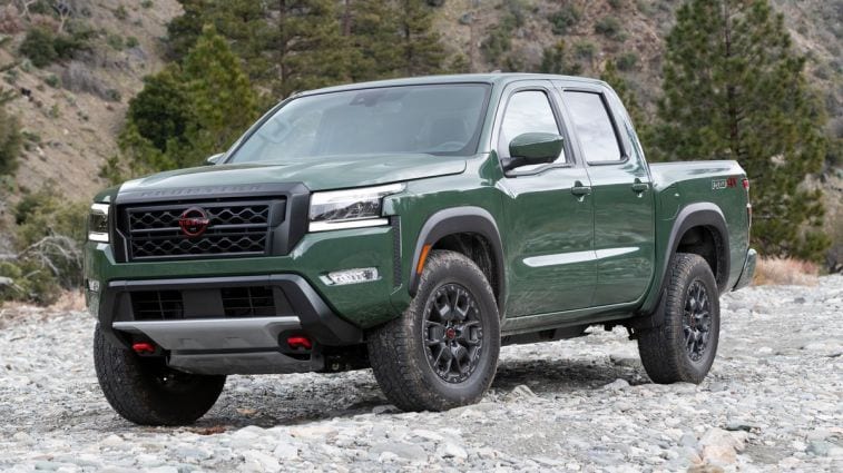 2024 Nissan Frontier PRO-4X parked on rocks with pine trees in the background.