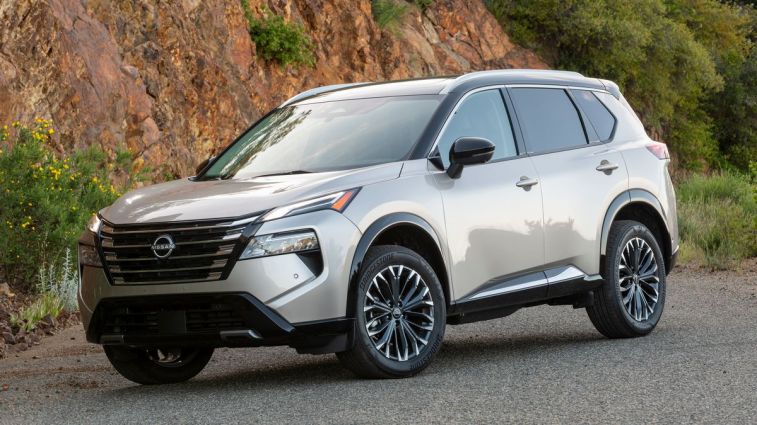 2024 Nissan Rogue Platinum with a rock wall in the background.