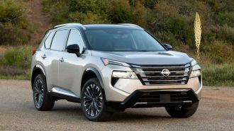 2024 Nissan Rogue Platinum with shrubs in the background.