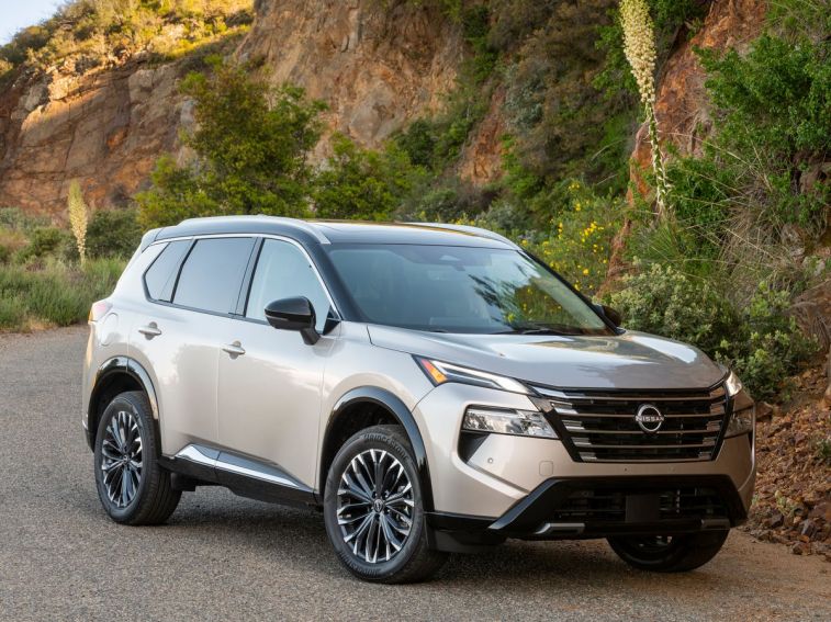 2024 Nissan Rogue Platinum with shrubs a rocky hill in the background.