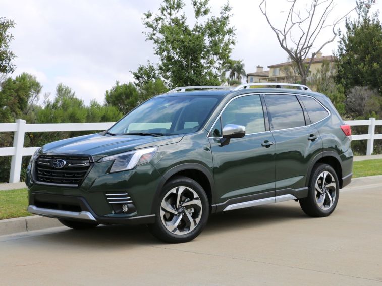 2024 Subaru Forester Touring with a white fence in the background.