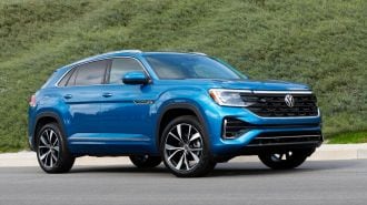 2024 Volkswagen Atlas Cross Sport in blue with a green hill in the background.