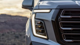 A teaser photo showing one headlight of the 2025 GMC Yukon