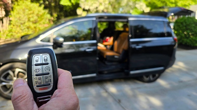 A Chrysler Pacifica key fob with the van's door open.
