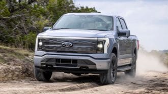 2024 F-150 Lightning Lariat driving on a dirt road.