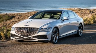 2024 Genesis G80 in white with the ocean in the background.