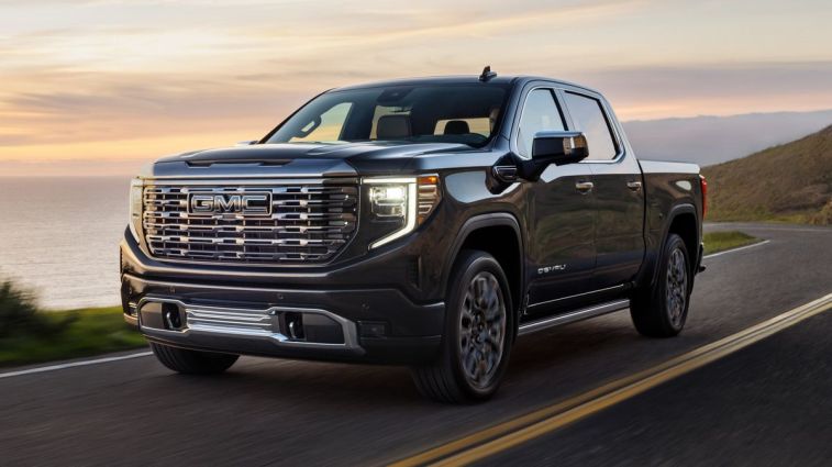 2024 GMC Sierra Denali Ultimate 1500 in Titanium Rush Metallic driving next to water.