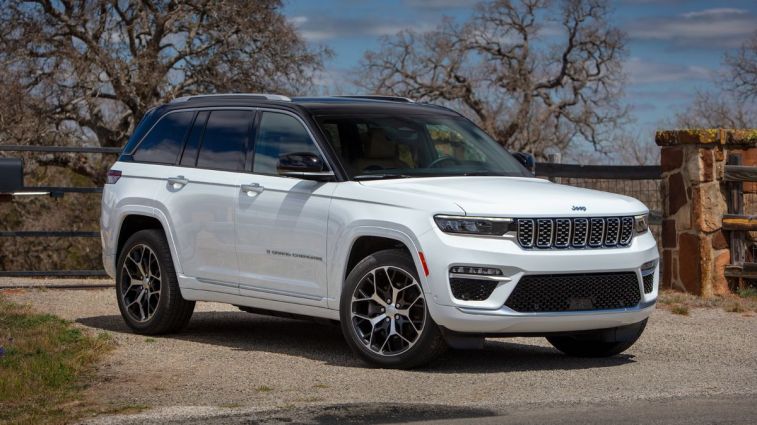 2024 Jeep Grand Cherokee Summit Reserve 4xe in white parked in front of a gate.