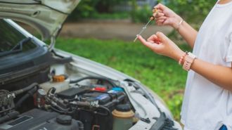 Woman checking engine oil level on the dipstick.
