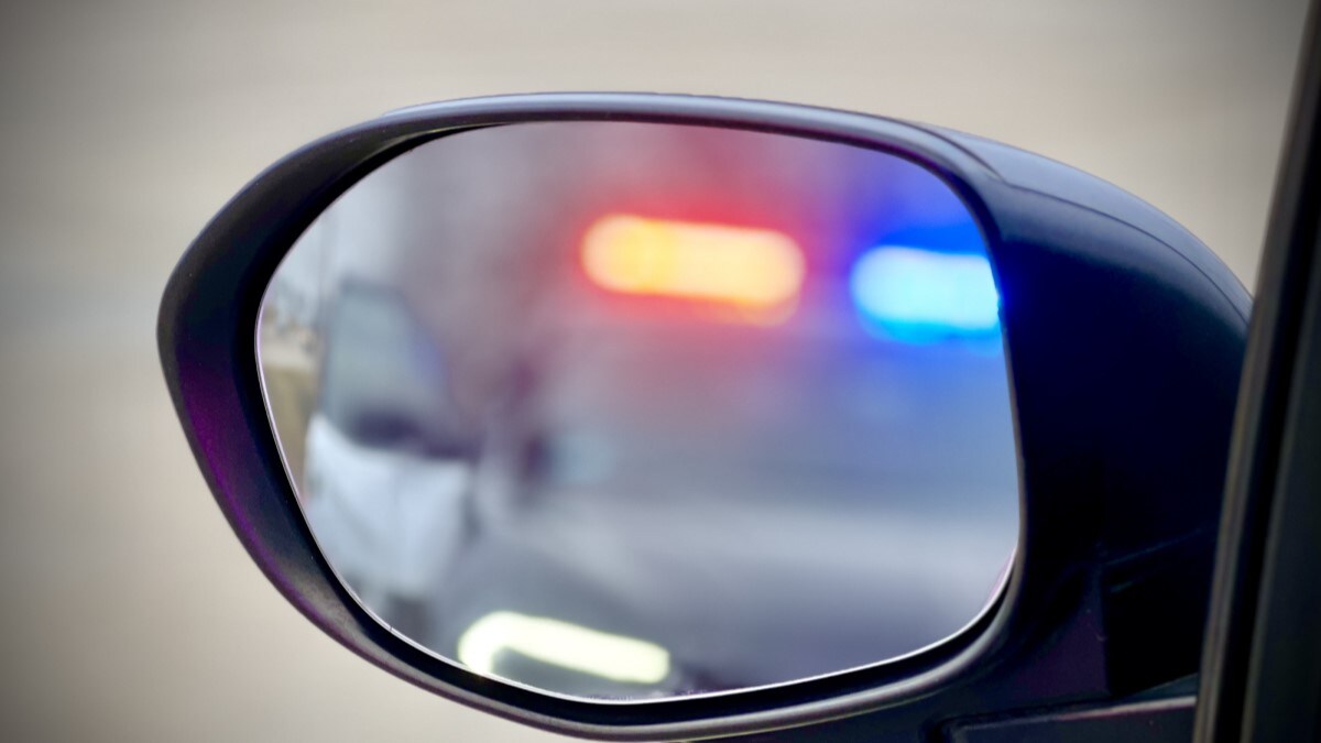 Police lights in a car's side mirror during a traffic stop