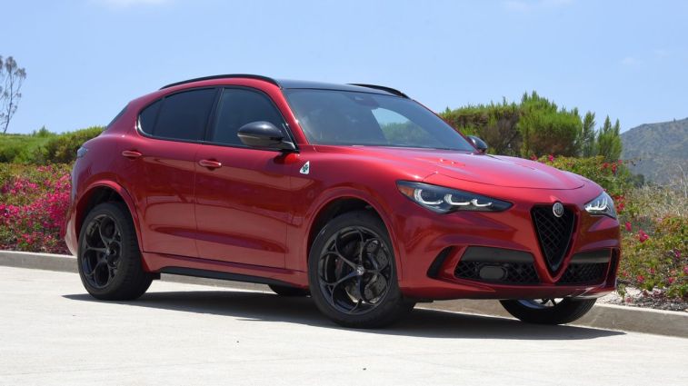 2024 Alfa Romeo Stelvio Quadrifoglio in Russo (Red) Etna with shrubs in the background.