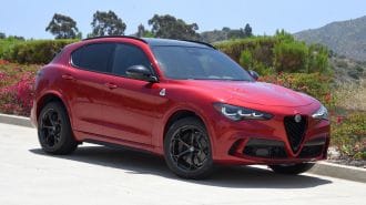 2024 Alfa Romeo Stelvio Quadrifoglio in Russo (Red) Etna with hills in the background.